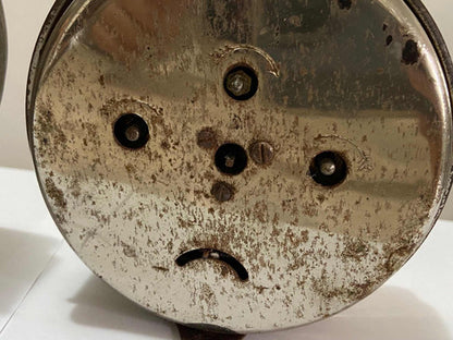 Bottom view of a vintage silver-colored alarm clock showing its winding keys and metal surface details