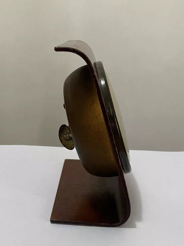 Side view of vintage wooden table clock with curved top and antique brass face winding key
