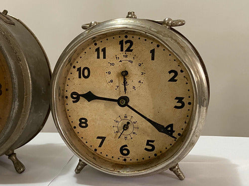 Vintage silver-colored analog alarm clock with classic round design and aged face showing time at 9:20