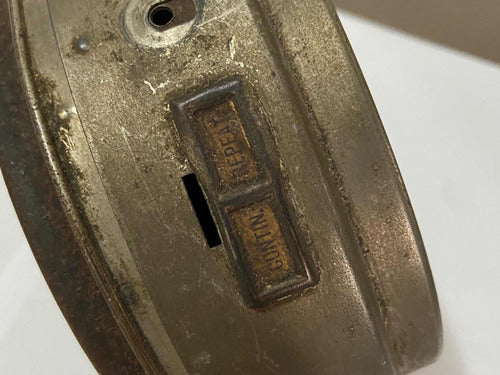 Close-up of the back of a vintage silver alarm clock showing the time adjustment switches.