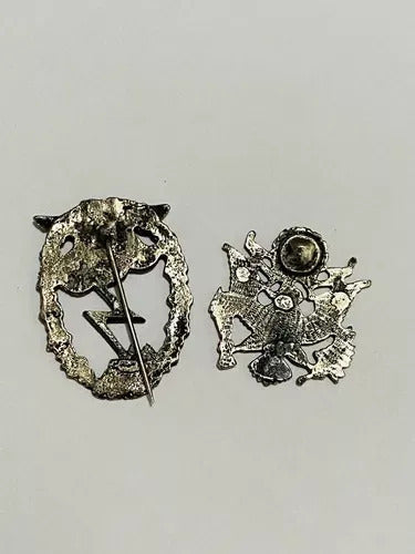 Back view of vintage World War II German and US military decoration and insignia pins on white background